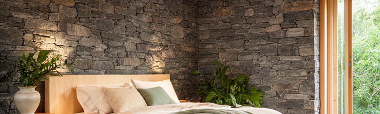 Interior de una suite ecológica con paredes de piedra local, madera certificada y luz natural